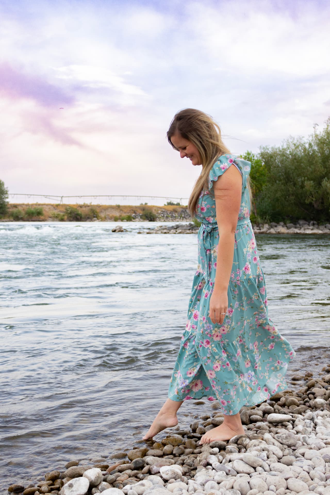 Shalese Bruce walking barefoot along the river at sunset