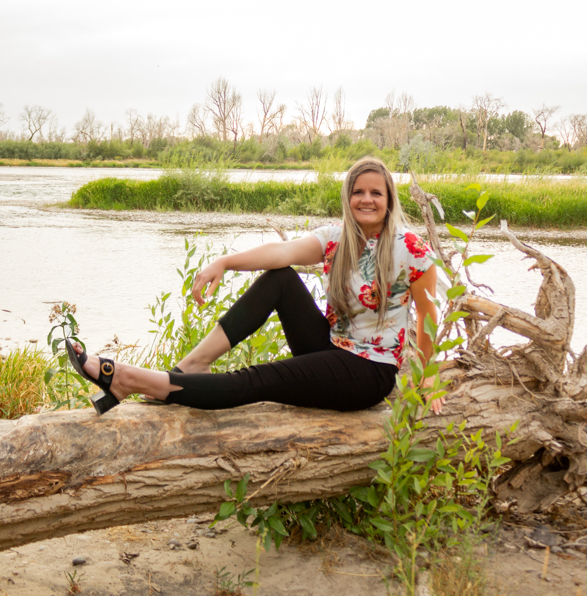 Shalese Bruce sitting on a fallen log beside the river